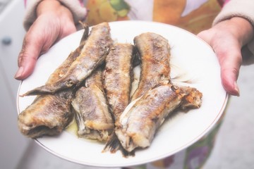Woman with plate of fried fish, hake