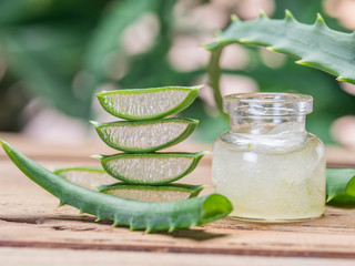 Fresh aloe leaves and aloe gel in the cosmetic jar on wooden table.