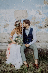 Beautiful bride and groom in front of old shabby house.