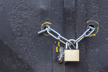 Padlock with chain on the iron gate. Black background. The concept protects reliably.