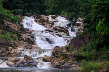 Cascade of Foamy Waterfalls in Stones against Trees