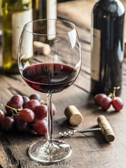 Glas rode wijn op tafel. Fles wijn en druiven op de achtergrond.