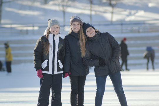 Portrait of three teenage girls wearing winter clothes at the rink