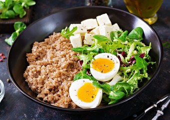 Healthy breakfast with egg, cheese, lettuce  and buckwheat porridge on dark background. Proper nutrition
