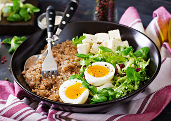 Healthy breakfast with egg, cheese, lettuce  and buckwheat porridge on dark background. Proper nutrition