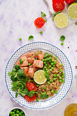 Healthy dinner. Slices of grilled salmon, quinoa, green peas, tomato, lime and lettuce leaves. Flat lay. Top view