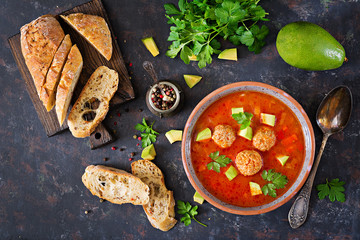 Spicy tomato soup with meatballs and vegetables. Served with avocado and parsley. Healthy dinner.Flat lay. Top view