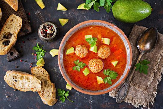 Spicy tomato soup with meatballs and vegetables. Served with avocado and parsley. Healthy dinner.Flat lay. Top view