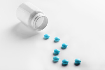 Medical blue pills and white bottle on white light background. Concept of healthcare and medicine.