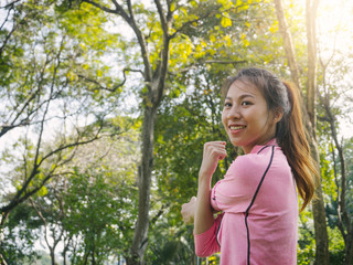 Close up of a young woman warm up her body by stretching her arms to be ready for exercising and do yoga in the park surrounded by nature and warm light afternoon sky. Outdoor workout exercise concept