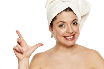 Young beautiful woman with towel on hr head on white background showing gun with her fingers