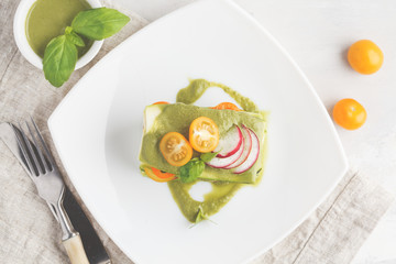 Raw vegan zucchini lasagna with vegetables and pesto sauce, light background. Vegetarian raw diet concept, top view.