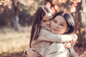 Fototapeta premium Close up image of mum and daughter holding each other in autumn garden.