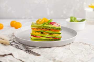 Raw vegan zucchini lasagna with vegetables and pesto sauce, light background. Vegetarian raw diet concept, copy space.