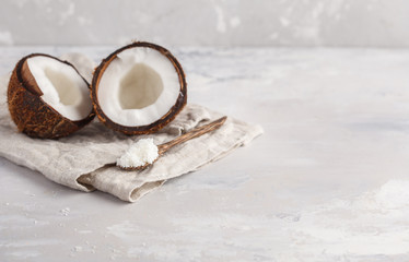 Open coconut with coconut shavings in a wooden spoon. Light background, copy space, vegan meal concept.