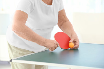 Senior woman playing table tennis indoors