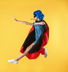 Cute girl as superhero on color background