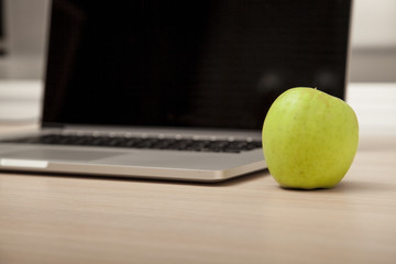 Conceptual photo, an green apple on a laptop as a symbol of knowledge and science