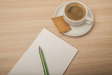 wooden desk with a notebook, top view, coffee and cookie 