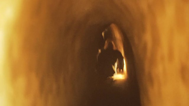 Blonde female shuffles on her backside through tight, small underground cu chi tunnels in Vietnam