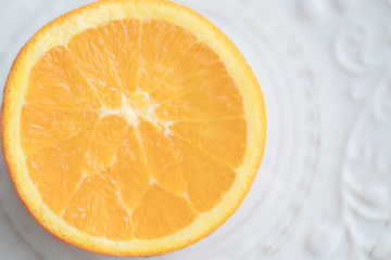 Orange cut in half pulp to the top on white patterned plate. Top view. Copy space