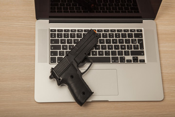 Conceptual photo, weapon on a laptop as a symbol of organized crime operating on the Internet, top view