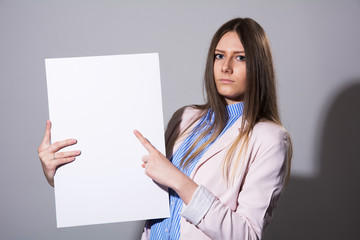 Naklejka premium Young serious woman pointing at white sheet