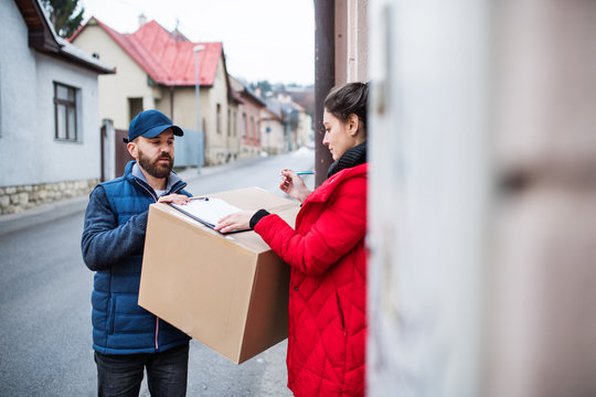 Woman Receiving Parcel From Delivery Man At The Door.