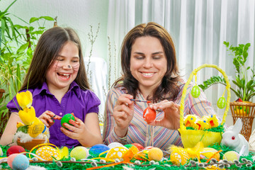 Mother and her children paint easter eggs