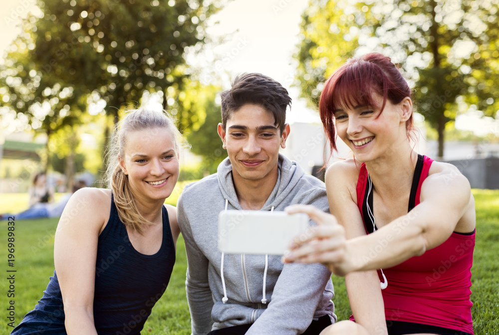 Canvas Prints Group of young runners with a smartphone in a park.