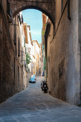 Narrow street of the old town on a sunny day, Siena, Italy
