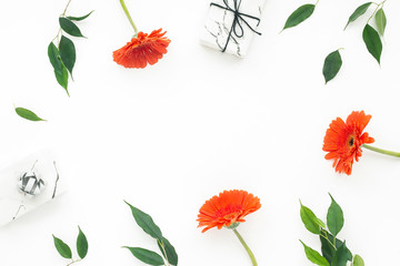 Orange flowers, gift, green leaves, on white background, flat lay, top view