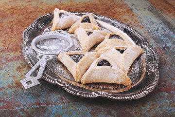 Hamantaschen cookies with poppy seed and risins and icing sugar on a plate, cooked for Jewish festival of Purim.