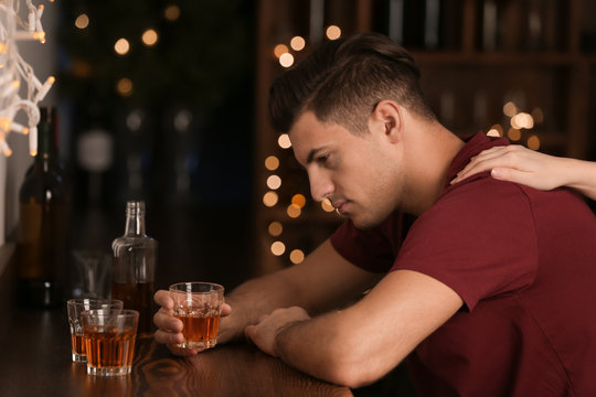 Young man with glass of drink in bar. Alcoholism problem