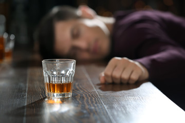Unconscious drunk man with glass of alcohol in bar. Alcoholism problem