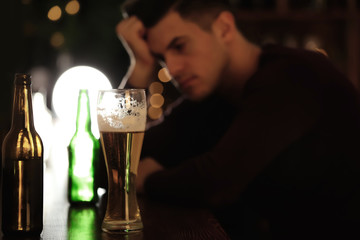 Glass of beer and blurred man on background. Alcoholism problem