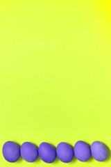 Row of painted violet easter eggs on yellow background, copy space. Healthy food concept. Top view, flat lay. Happy Easter concept