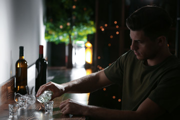 Young man pouring drink into glass at bar. Alcoholism problem