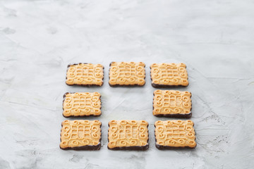 Square biscuits arranged in pattern on light textured background, close-up, shallow depth of field, selective focus.