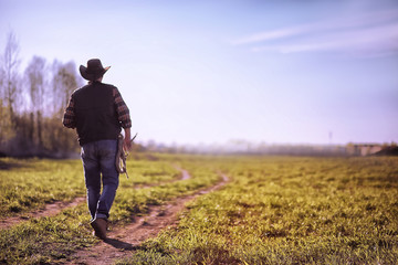 Cowboy standing in a field at sunset