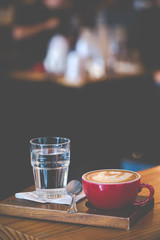 Red cups of Late coffee with froth swan shaped on table at coffee shop