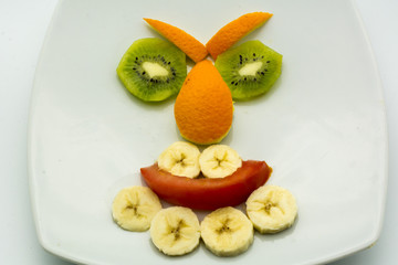Horizontal View of Close Up some Pieces of Fruit Forming a Face Expression with Banana, Kiwi, Orange and Tomato on White Background