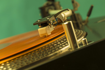 Fototapeta na wymiar Closeup of turntable needle on orange coloured vinyl record