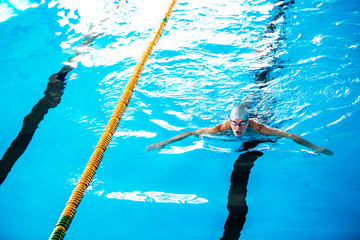 Senior man swimming in an indoor swimming pool.