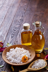 SPA concept: composition of spa treatment with natural sea salt, aromatic oil and flowers on wooden background