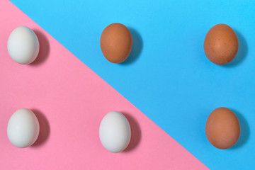 White and brown eggs on blue and pink pastel background, copy space. Boiled eggs on paper background with two tone color. Healthy food concept. Easter eggs. Flat lay, top view