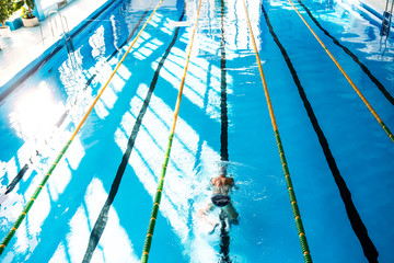 Senior man swimming in an indoor swimming pool.