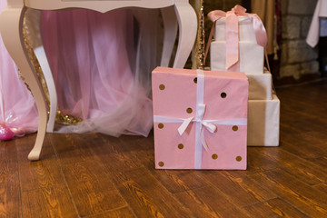 The gift is packed in pink paper with golden circles and bandaged with a white ribbon. Birthday
