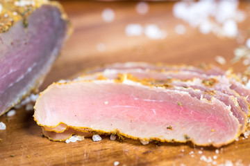 Close up of a cutting board with dried meat on brown background