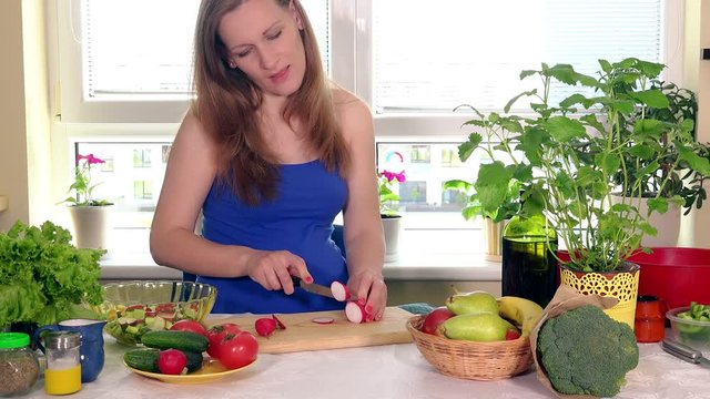 Pregnant woman cutting radish vegetables on cutting board